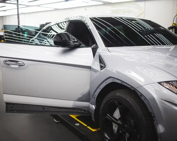 A silver SUV with its door open in a bright, clean service bay