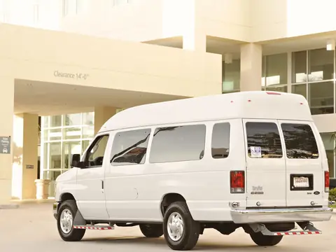A white passenger van parked outside a building