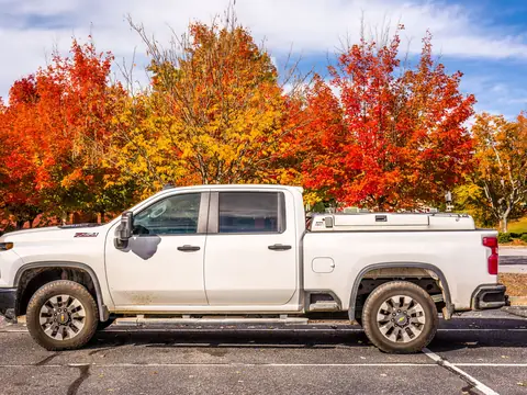A white pickup parked under trees in autumn colour